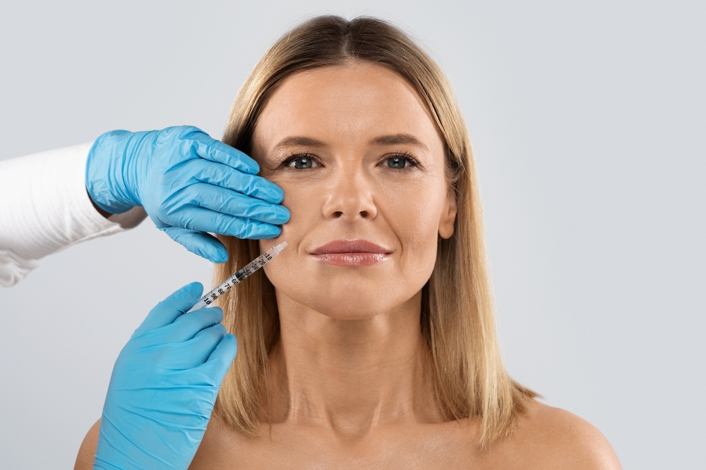 Middle aged woman receiving Restylane injections to her nasolabial folds to minimize fine lines and signs of aging.