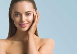 Smiling woman with slicked back hair touching her eyebrow area after treatment