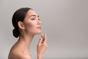 Close up of a woman having her nose drawn on in preparation for a rhinoplasty or nose reshaping surgery. Beautiful woman touching their chin after getting a chin augmentation for a more proportional profile.